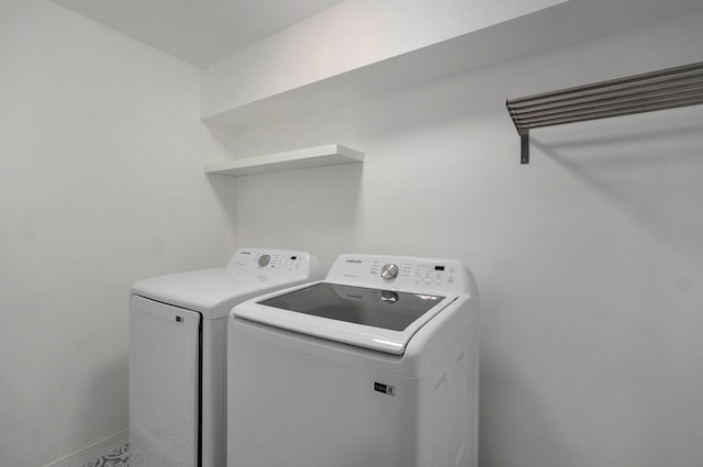 washroom with laundry area, washer and clothes dryer, and baseboards