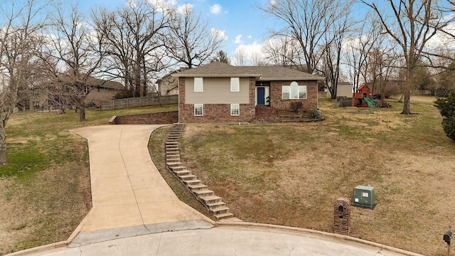 view of front of property featuring a front yard, fence, a playground, and brick siding