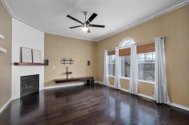 interior space featuring baseboards, a ceiling fan, ornamental molding, wood finished floors, and a fireplace