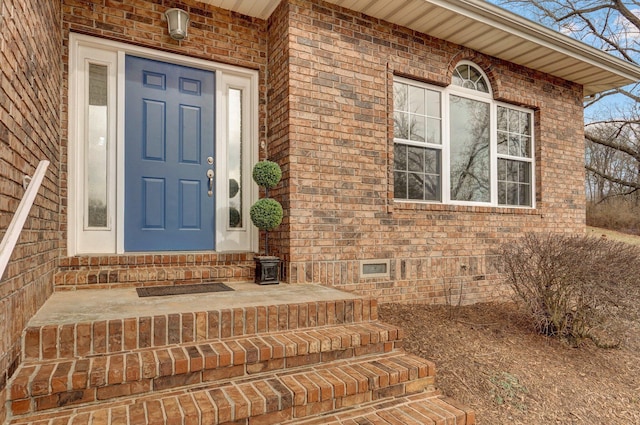 entrance to property featuring crawl space and brick siding