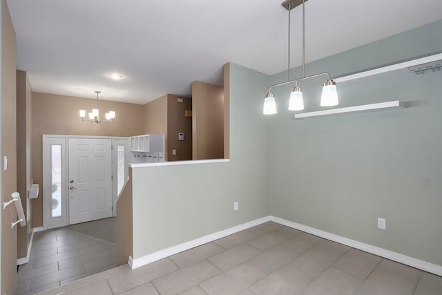 tiled foyer with a notable chandelier and baseboards