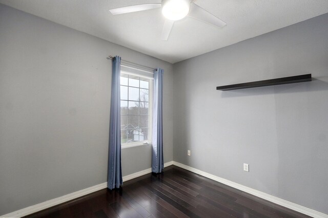 unfurnished room with a ceiling fan, baseboards, and dark wood-type flooring