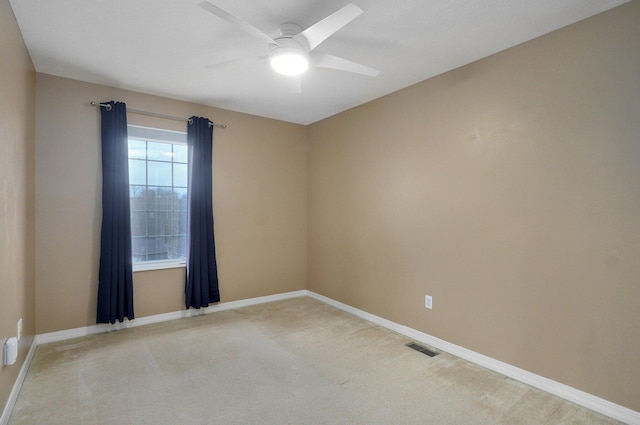 spare room with ceiling fan, visible vents, light colored carpet, and baseboards