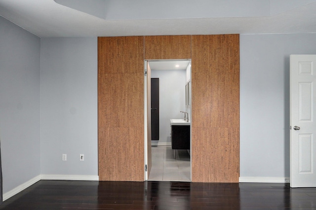 unfurnished room featuring a sink, wood finished floors, and baseboards