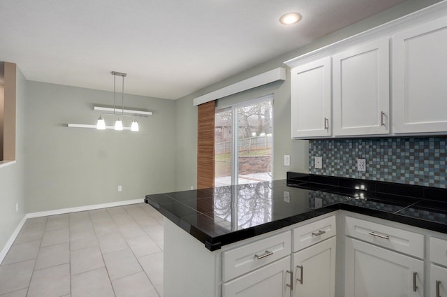 kitchen featuring a peninsula, baseboards, white cabinets, backsplash, and pendant lighting