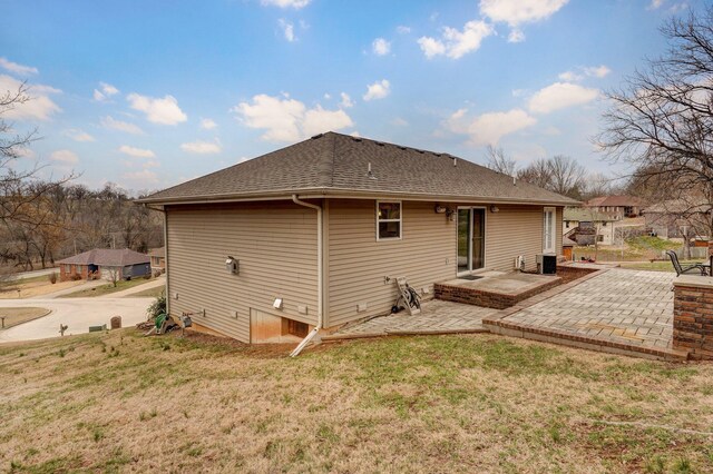 back of property featuring a yard, roof with shingles, and a patio area