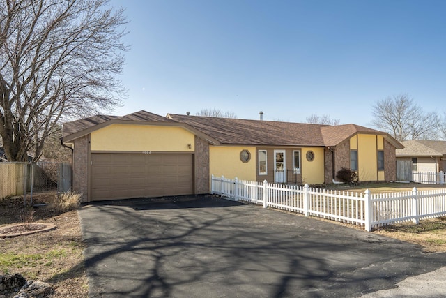 single story home with driveway, a fenced front yard, an attached garage, and stucco siding