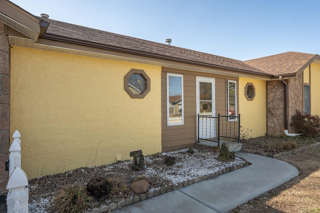 doorway to property with a shingled roof and stucco siding