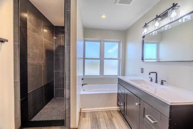 bathroom with a garden tub, wood finished floors, a tile shower, and visible vents