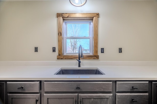 kitchen with light countertops, a sink, and gray cabinetry