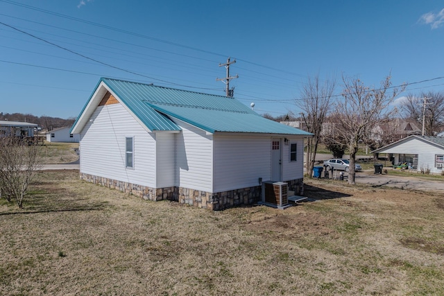 view of side of property with a yard, metal roof, and central AC unit