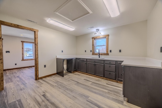 laundry room featuring light wood-style flooring, a sink, visible vents, and baseboards