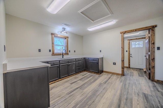 kitchen with light countertops, light wood-type flooring, a sink, and visible vents