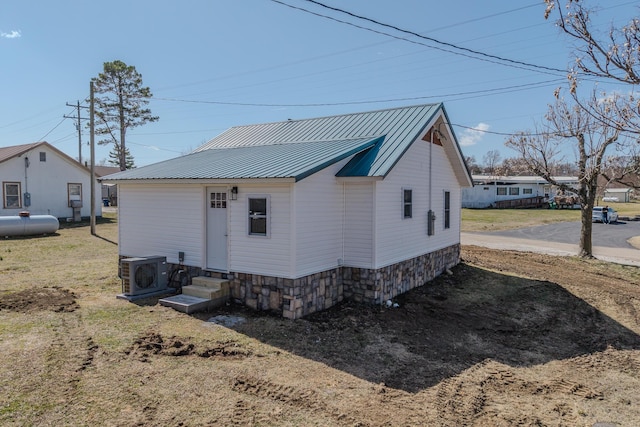 back of property with entry steps, ac unit, and metal roof