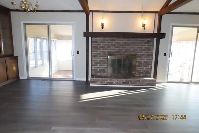 unfurnished living room featuring beam ceiling, a brick fireplace, and a healthy amount of sunlight