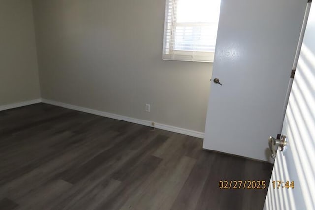 empty room with baseboards and dark wood-style floors