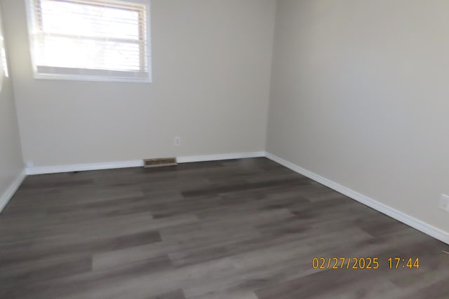 unfurnished room featuring visible vents, baseboards, and dark wood-style floors