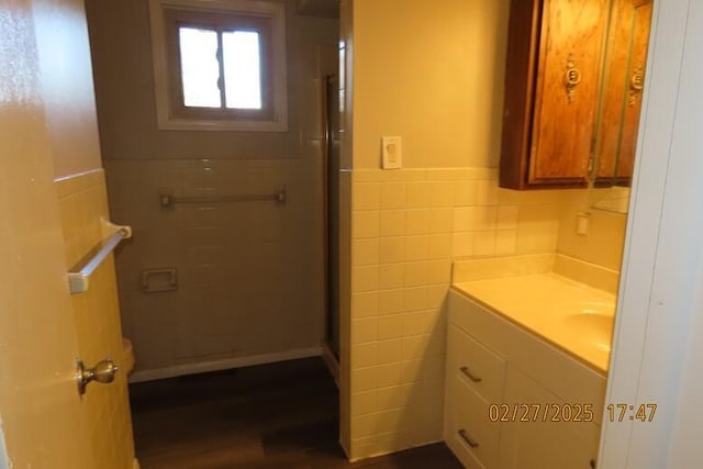 full bath with wood finished floors, tile walls, a stall shower, and vanity