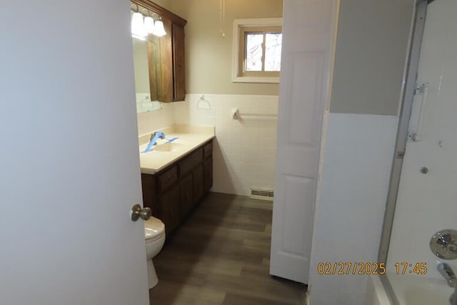 full bathroom with toilet, vanity, wainscoting, wood finished floors, and tile walls