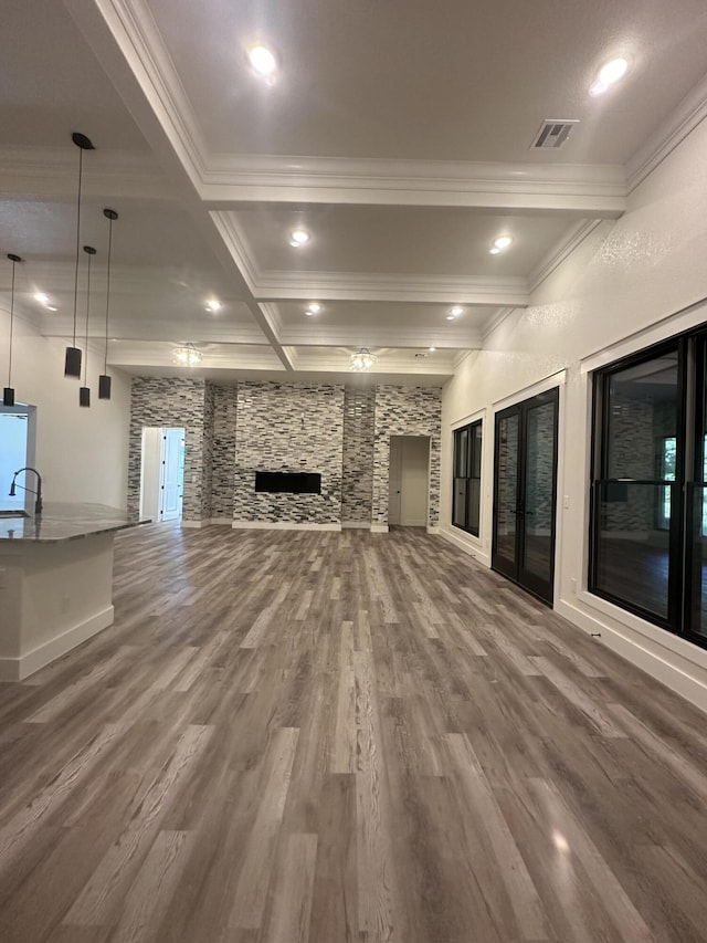 unfurnished living room featuring a fireplace, wood finished floors, visible vents, ornamental molding, and beam ceiling