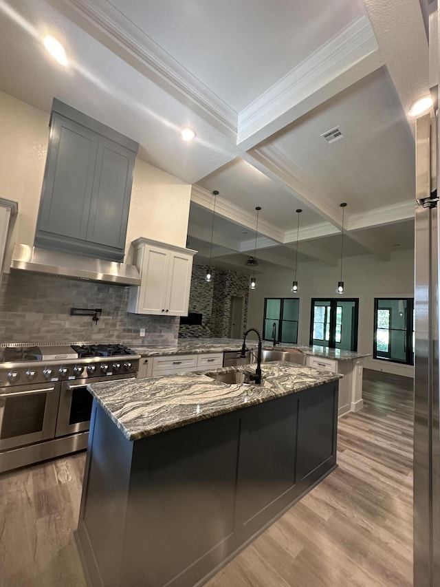 kitchen with a spacious island, a sink, visible vents, light wood-style floors, and double oven range