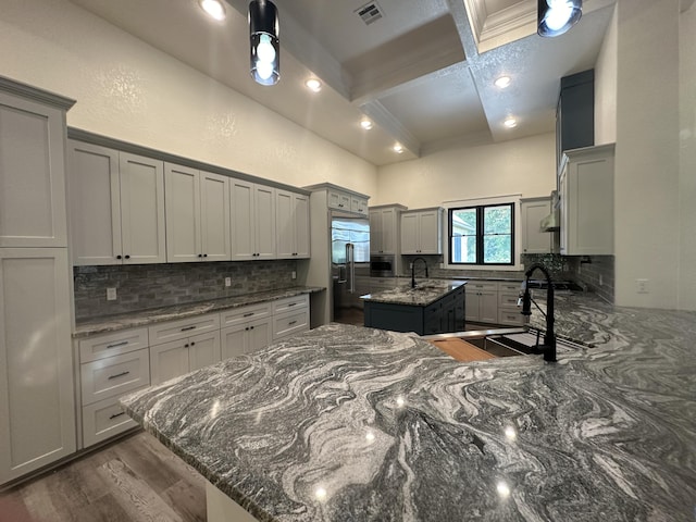 kitchen featuring coffered ceiling, gray cabinets, visible vents, and a center island with sink