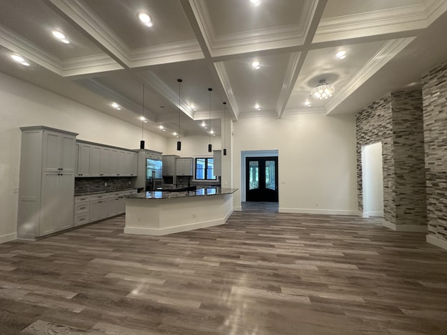 kitchen with dark wood finished floors, open floor plan, a high ceiling, crown molding, and beam ceiling