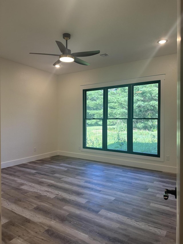 empty room with visible vents, dark wood-style flooring, and a wealth of natural light