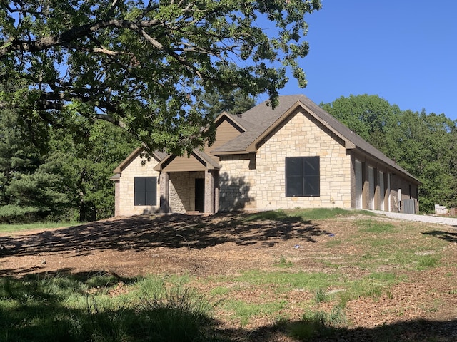 view of front of property featuring stone siding and a shingled roof