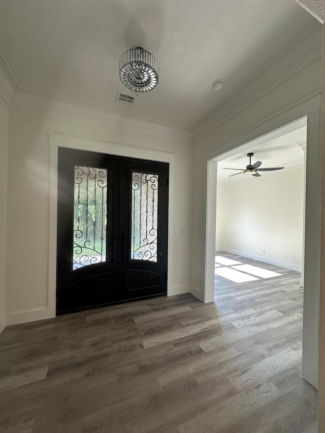 foyer with ornamental molding, visible vents, and wood finished floors