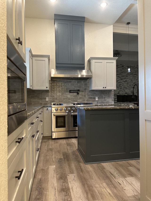 kitchen featuring backsplash, a sink, wood finished floors, built in microwave, and double oven range