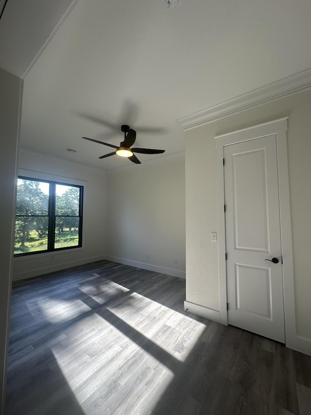 unfurnished room featuring ornamental molding, wood finished floors, a ceiling fan, and baseboards