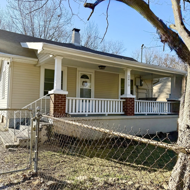 view of front of home featuring a porch, a gate, fence, and a chimney