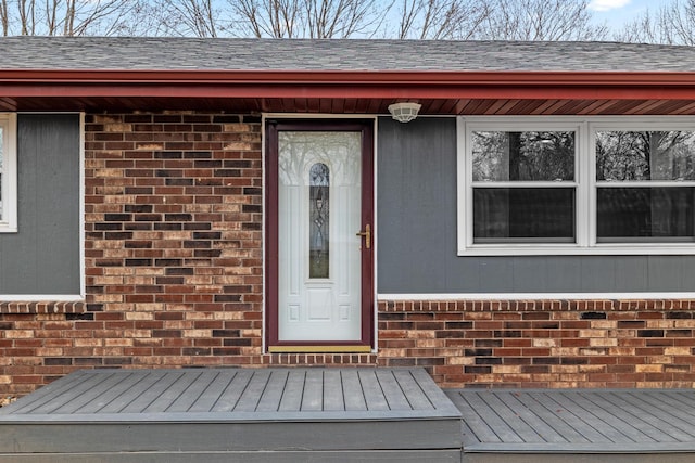 property entrance with brick siding and a shingled roof