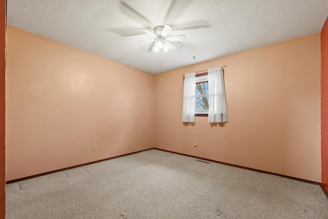 empty room featuring a textured ceiling, baseboards, and light carpet