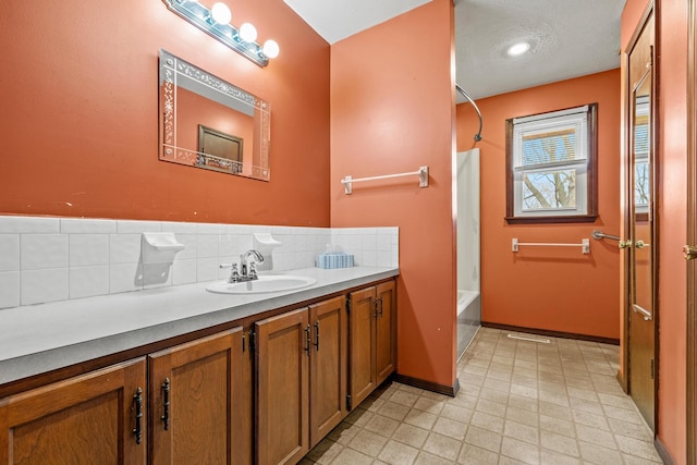 full bath featuring tile patterned floors, shower / bath combo with shower curtain, backsplash, baseboards, and vanity