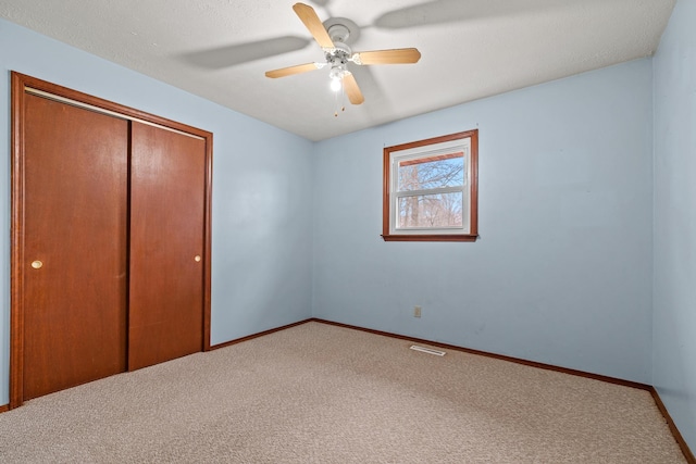 unfurnished bedroom with visible vents, baseboards, ceiling fan, carpet flooring, and a closet