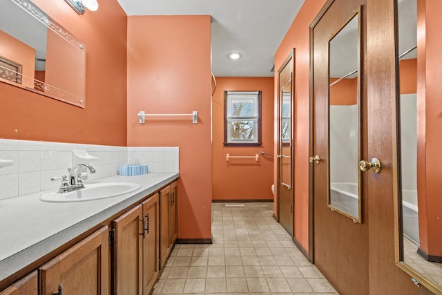 bathroom with baseboards, backsplash, vanity, and toilet