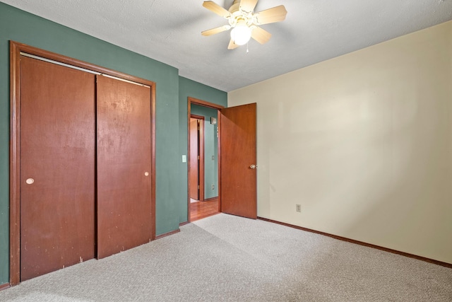 unfurnished bedroom with a textured ceiling, a closet, carpet flooring, baseboards, and ceiling fan