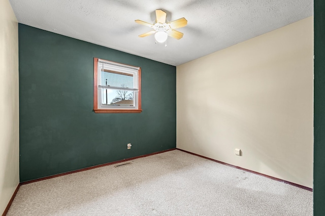 carpeted empty room with visible vents, baseboards, a textured ceiling, and a ceiling fan