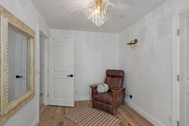 sitting room with wood finished floors, baseboards, and a chandelier