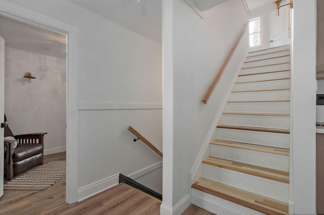 staircase featuring wood finished floors and baseboards