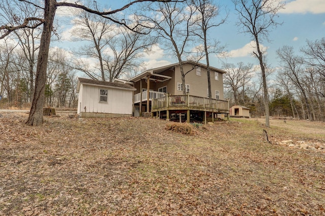 back of property with an outbuilding, a shed, and a wooden deck