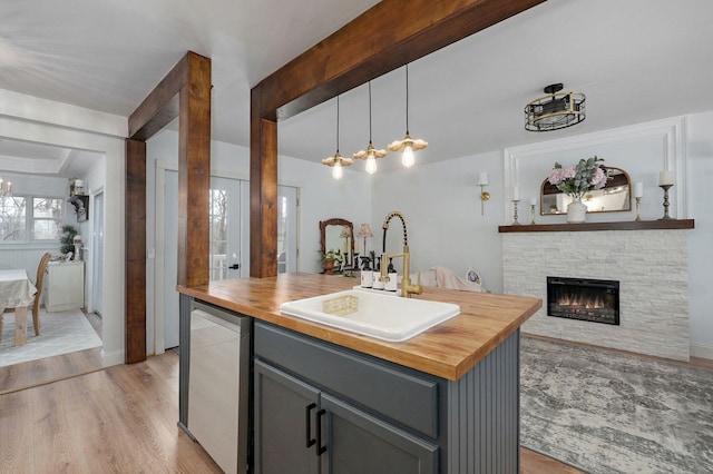 kitchen with butcher block countertops, gray cabinetry, light wood-type flooring, and a sink