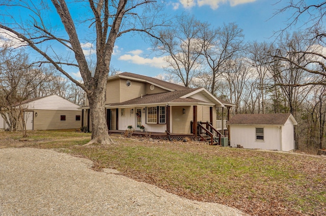 view of front facade with an outbuilding, covered porch, and a front lawn