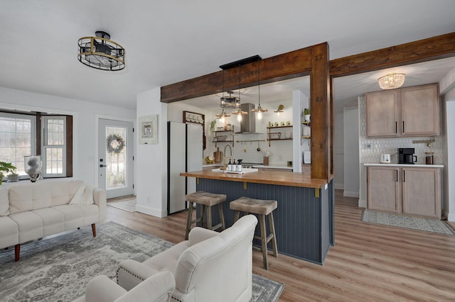 living area with baseboards, beam ceiling, and light wood-style floors