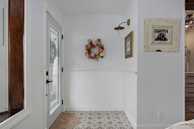 entryway with tile patterned floors and a wainscoted wall