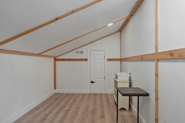 additional living space featuring vaulted ceiling, wood finished floors, visible vents, and baseboards