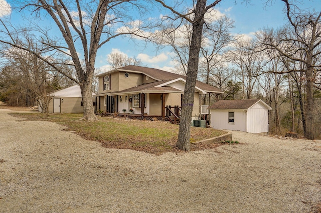 view of front of house with a storage unit, central air condition unit, an outbuilding, and a porch