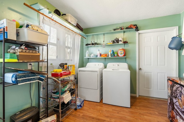 washroom featuring a textured ceiling, wood finished floors, laundry area, and washing machine and clothes dryer